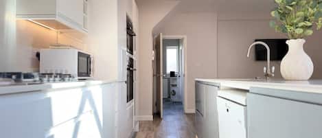 Una cocina moderna con armarios blancos, un microondas y un lavamanos.