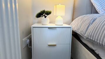 A white bedside table with a lamp and a small potted plant.