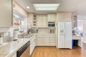 A modern kitchen with white cabinetry, a built-in dishwasher, and a refrigerator. - Oakhurst 3BR - Hot Tub, Games & Yosemite (Oakhurst)