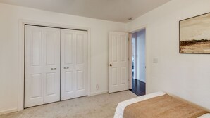 Quarto com cama, corredor e duas portas brancas.
