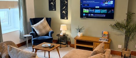 A living room with a sofa, armchair, coffee table, lamp, TV, and decorative items.
