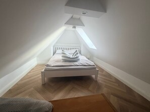 A bedroom with a sloped ceiling, a bed, a nightstand, and a skylight. - Exquisite Vacation Home "Naturally on the Bodden" on the Baltic Sea, including Wi-Fi and parking - (Fuhlendorf)