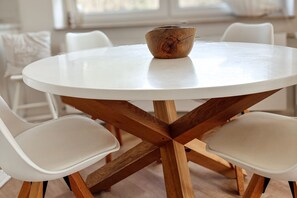 A round table with a white top and wooden base, surrounded by four white chairs. - Exquisite Vacation Home "Naturally on the Bodden" on the Baltic Sea, including Wi-Fi and parking - (Fuhlendorf)