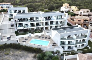 Un hôtel moderne à plusieurs étages, doté d’une piscine sur le toit, de balcons et d’un jardin aménagé.