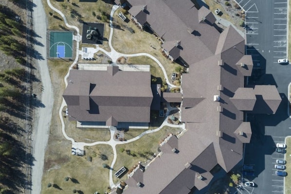 An aerial view of a residential area with multiple houses, a basketball court, and a parking lot.