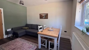 A living room with a sofa, a dining table, and a window. - The New Forest 2-bed Apt, Sleeps 6 With Garden (Southampton)