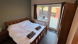 A bedroom with a bed, a window, and a door leading to an outdoor area. - The New Forest 2-bed Apt, Sleeps 6 With Garden (Southampton)