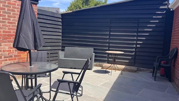 An outdoor patio with a round table, two chairs, a small round table, and a covered umbrella. - The New Forest 2-bed Apt, Sleeps 6 With Garden (Southampton)