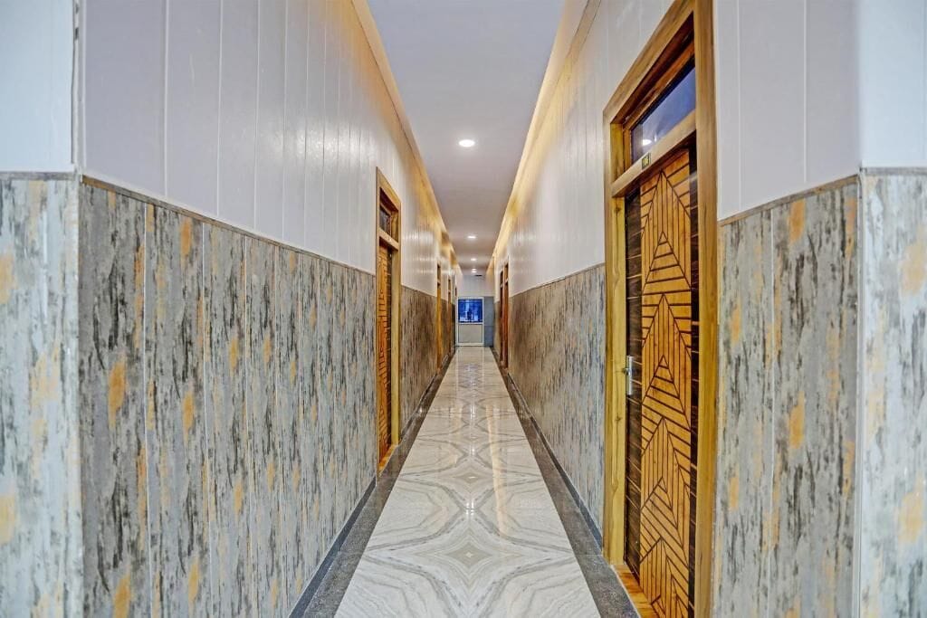Un pasillo con paredes y puertas de mármol, que conduce a una habitación con un letrero azul.