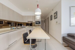 Una cocina moderna con una isla central, un comedor con sillas y un sofá.