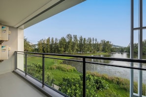 Un balcón con vistas a un río, árboles y una zona verde.