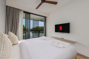 A hotel room with a bed, a television mounted on the wall, and a view of the outdoors through a sliding door. - Cassia Phuket Bang Tao by Tropiclook (Choeng Thale)