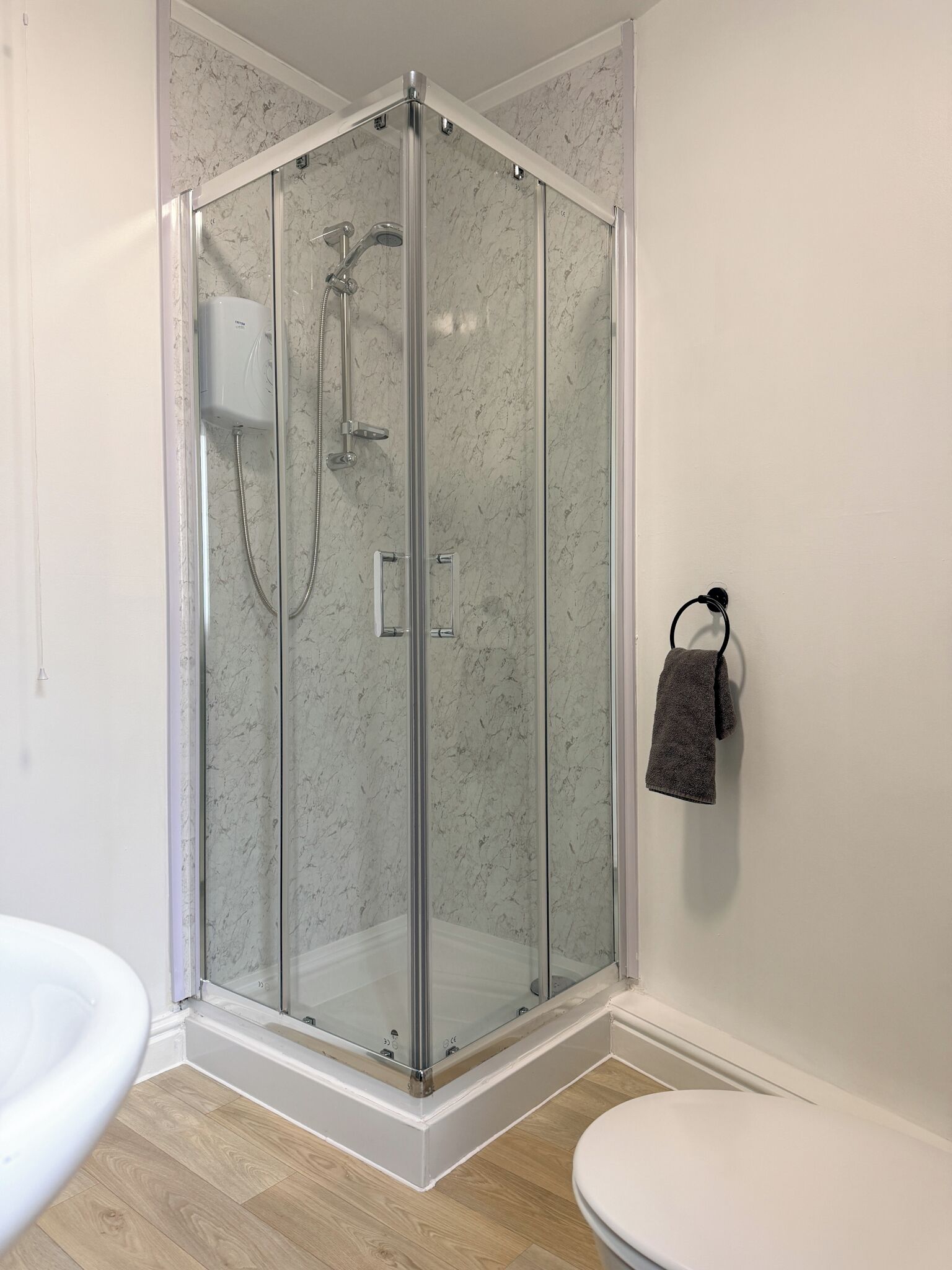 A modern bathroom with a glass-enclosed shower, a toilet, and a sink.