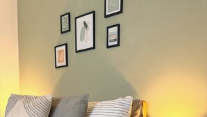 A bedroom with a bed, pillows, a bedside table with a lamp, and framed pictures on the wall.