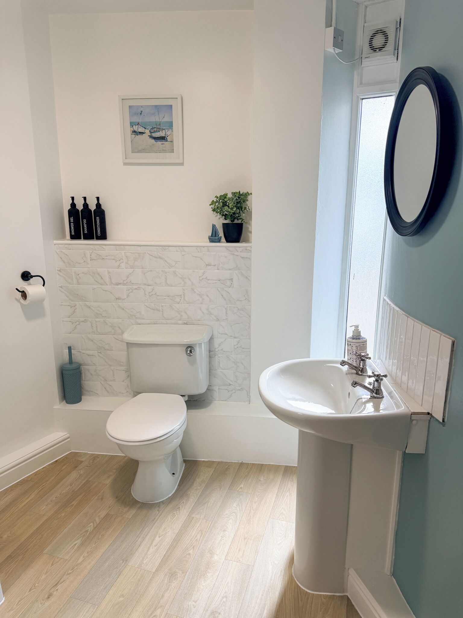 A bathroom with a toilet, sink, and a potted plant.