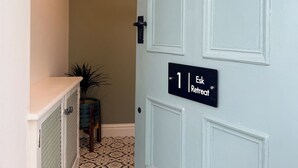 A hallway with a door labeled '1 | Esk Retreat' and a small plant on a table.