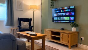 A living room with a television mounted on the wall, a sofa, a coffee table, and a rug.