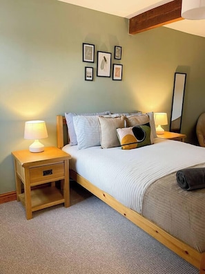 A bedroom with a bed, bedside tables, a lamp, a mirror, and framed pictures on the wall.