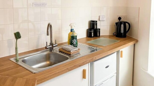 A compact kitchen with a sink, a coffee maker, and a small refrigerator.