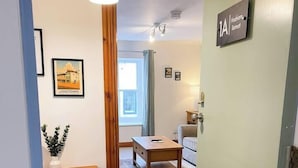 A hallway with a wooden bench, a small table, and a door labeled '1A'.