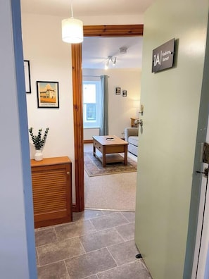 A hallway with a wooden bench, a small table, and a door labeled '1A'.