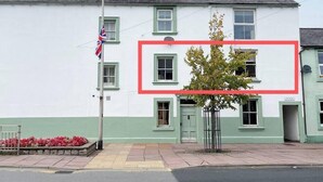 A building with multiple windows, a flag, and a tree in front.