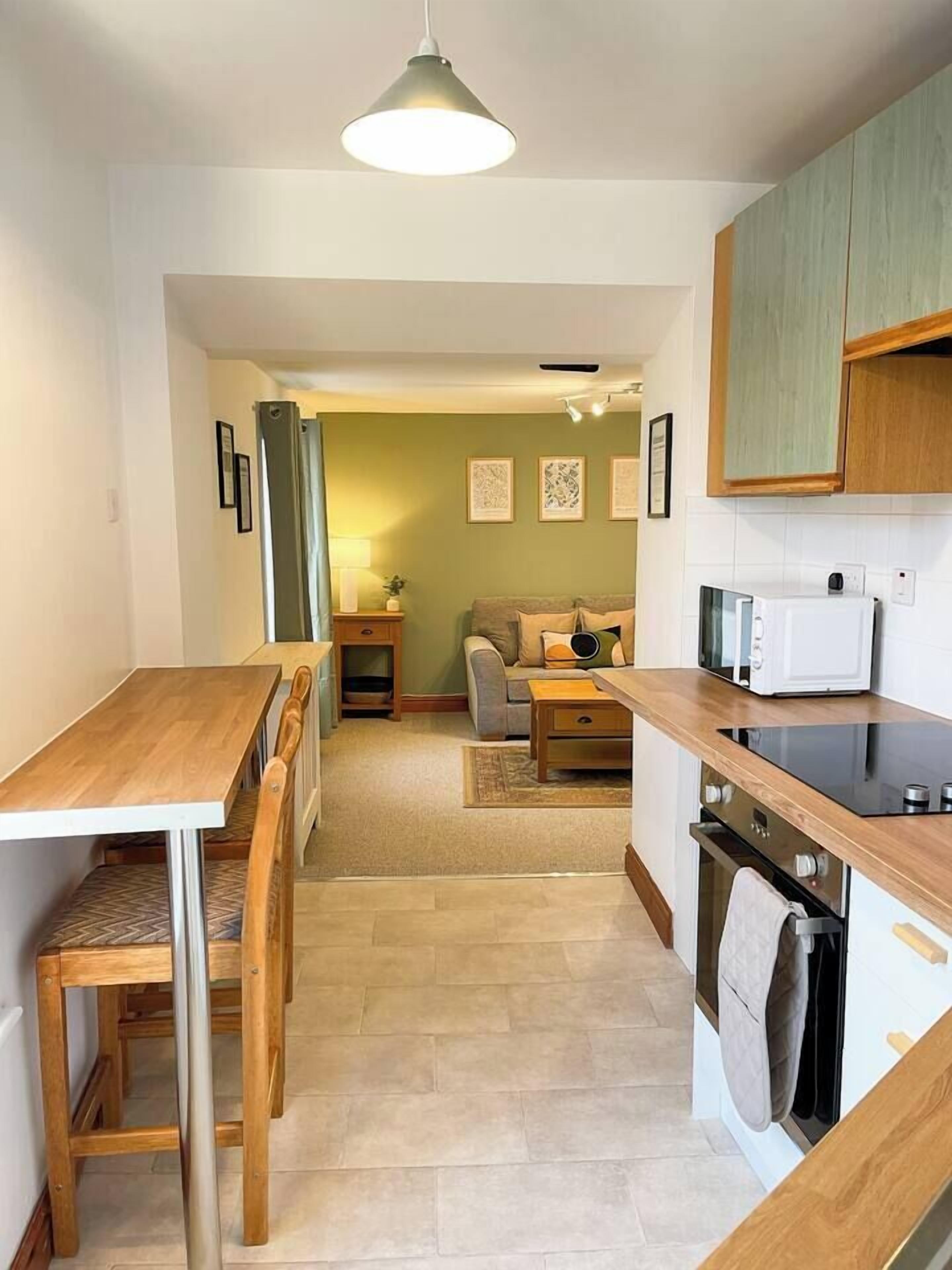 A compact kitchen with a dining table and chairs, a microwave, and a stove.