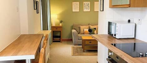 A compact kitchen with a dining table and chairs, a microwave, and a stove.