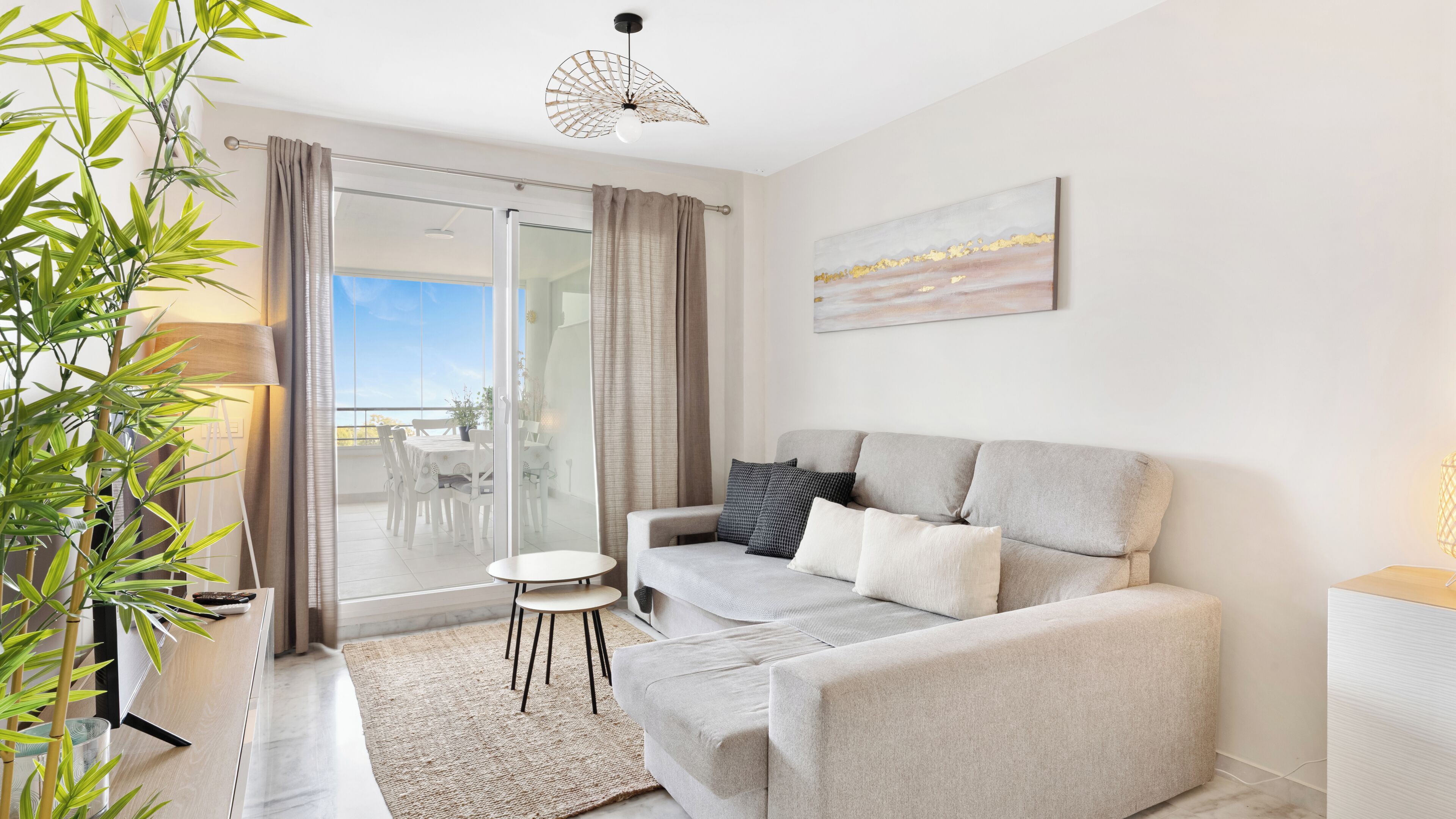 Een moderne woonkamer met een bank, een bijzettafeltje en een potplant.