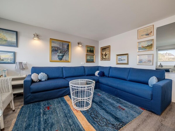A living room with a blue sectional sofa, a white metal coffee table, and a blue rug. - defaultName (Sylt)