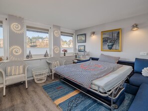 A bedroom with a bed, two chairs, a small table, and a window with a view. - defaultName (Sylt)