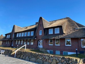 A large, two-story building with a steeply pitched roof and a stone foundation. - defaultName (Sylt)
