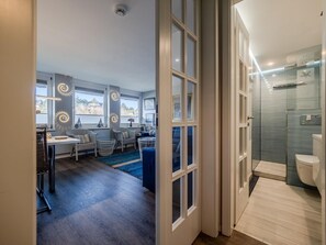 A modern interior with a dining area, kitchen, and a bathroom with a shower and toilet. - defaultName (Sylt)