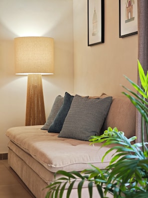 Un canapé agrémenté de plusieurs coussins, un lampadaire et des œuvres d’art encadrées accrochées au mur.