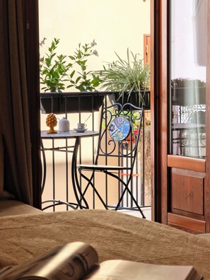 Un balcon avec une table, des chaises et des plantes en pot.