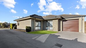 Ett modernt hus i två våningar med garage, stora fönster och en välskött gräsmatta.