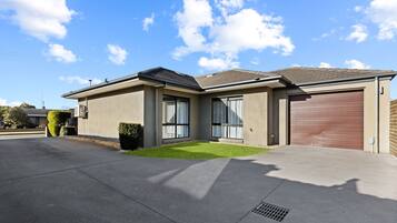 A modern two-story house with a garage, large windows, and a well-maintained lawn.
