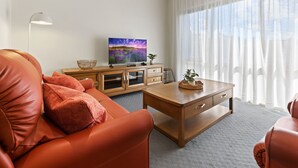 Ett modernt vardagsrum med en soffa i läder, ett soffbord i trä och en platt-TV placerad på ett träskåp.