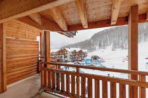 Un balcó de fusta amb vista a una estació d'esquí nevada.