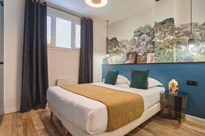 A hotel room with a bed, a nightstand, a window with curtains, a wall with a nature-themed mural, and a ceiling light. - Apartment in the center of Paris (Paris)