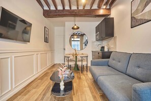 A modern living room with a grey sofa, a round mirror, and a small table with a vase. - Apartment in the center of Paris (Paris)