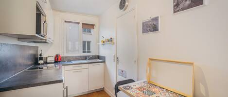 A compact kitchen with a dining area, a small table, and a chair.