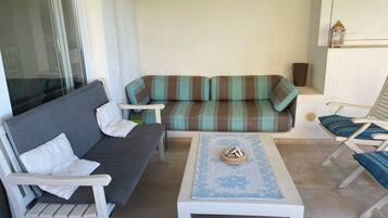 Ein möblierter Wohnbereich mit Sofa, zwei Sesseln, einem Couchtisch und einem kleinen Dekoartikel.