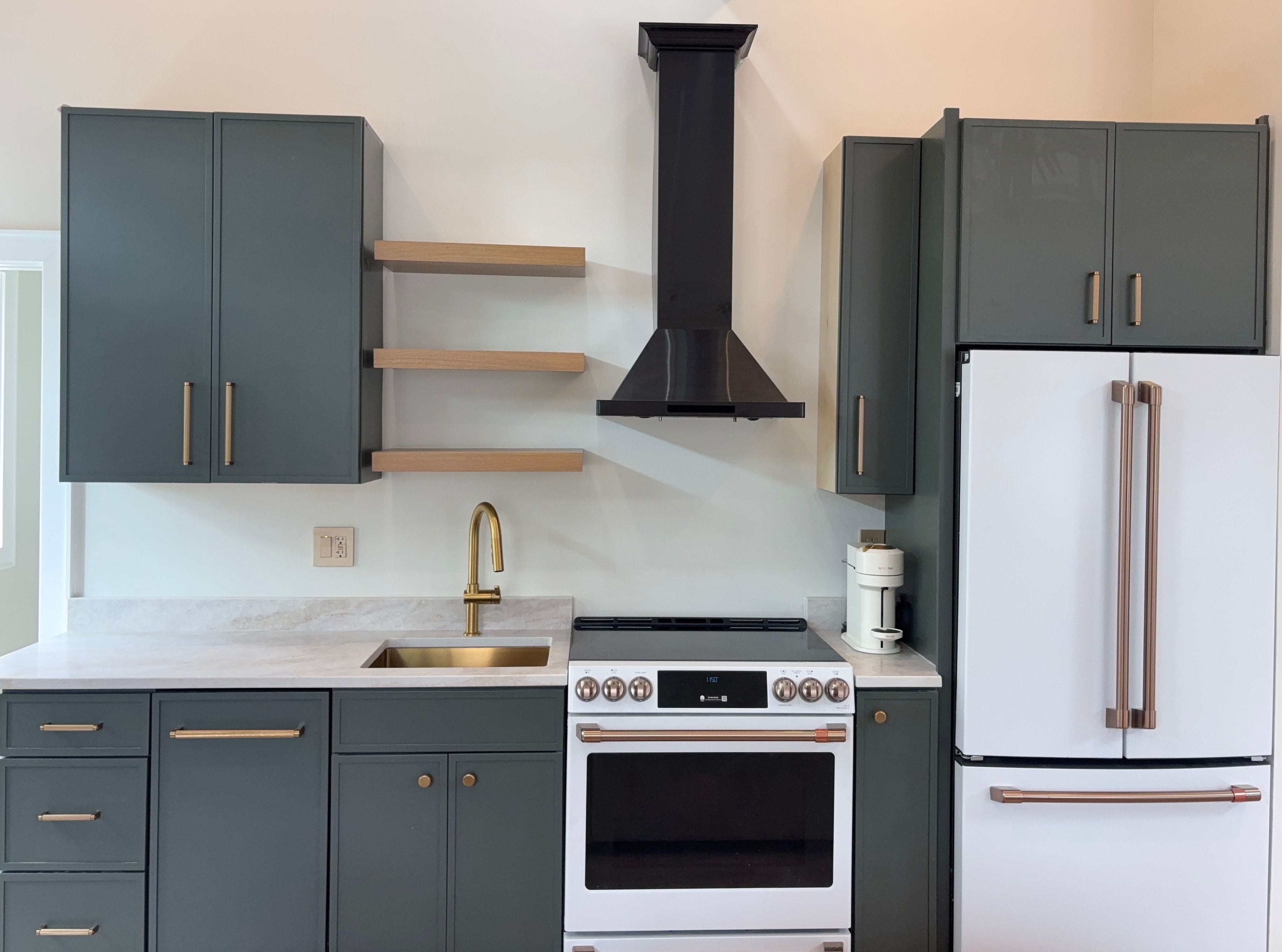 Une cuisine avec des meubles de couleur sombre, un évier en acier inoxydable, une cuisinière blanche et un réfrigérateur blanc.