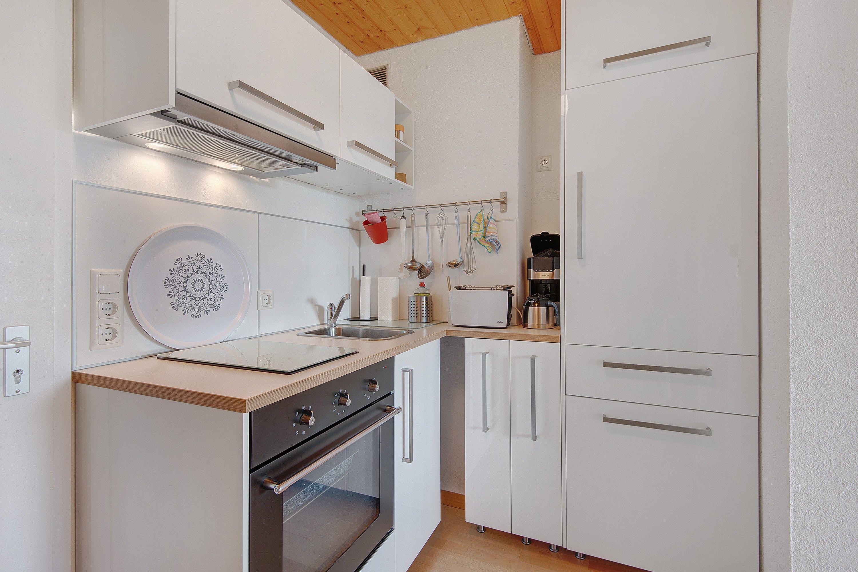 Une cuisine moderne avec des meubles blancs, une cuisinière en acier inoxydable et un four encastré.