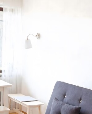 A room with a white desk, a grey upholstered chair, and a wall-mounted lamp. - Apartment 'Traum Im Bayrischen Wald' with Balcony and Wi-Fi (Wiesenfelden)