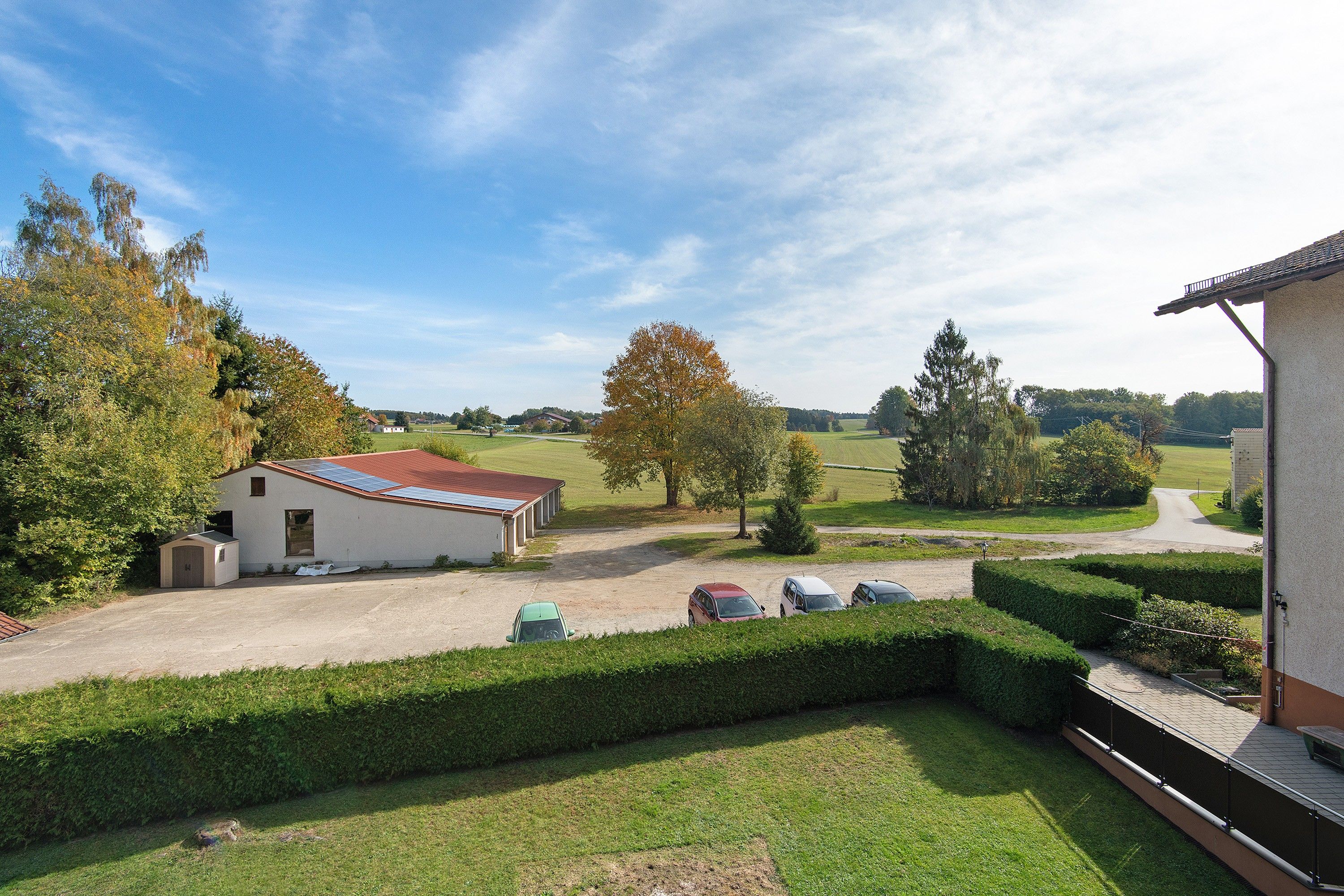 Une propriété rurale avec un bâtiment blanc, une construction à toit rouge et une pelouse bien entretenue.