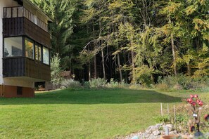 Ein modernes, zweistöckiges Gebäude mit großen Fenstern, umgeben von einem gepflegten Rasen und dichtem Wald.
