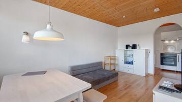 A modern kitchen with a built-in oven, a dining area with a table and bench, and a cozy seating area with a sofa.