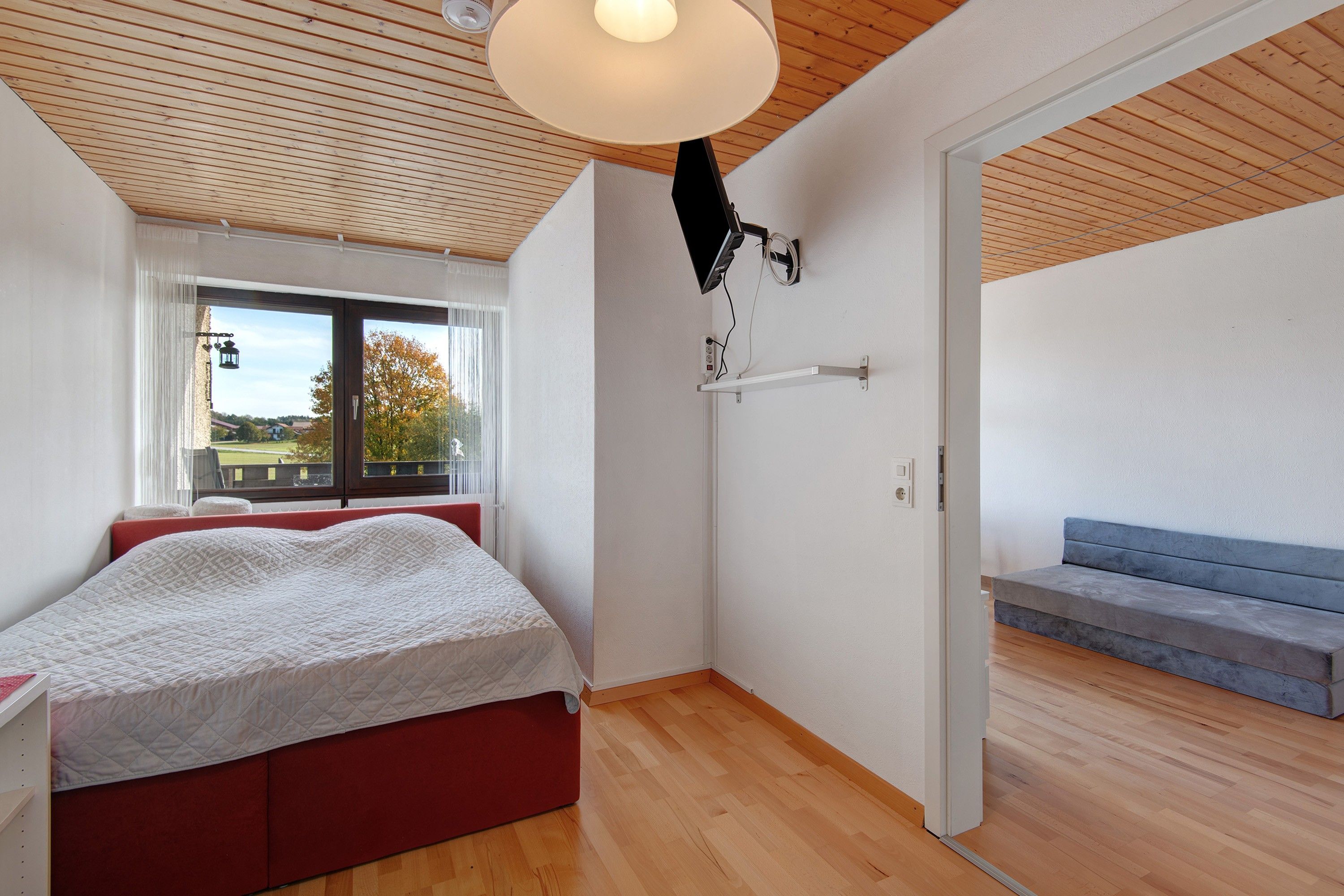 Ein Schlafzimmer mit Bett, Fenster, Schreibtisch und einer Treppe.